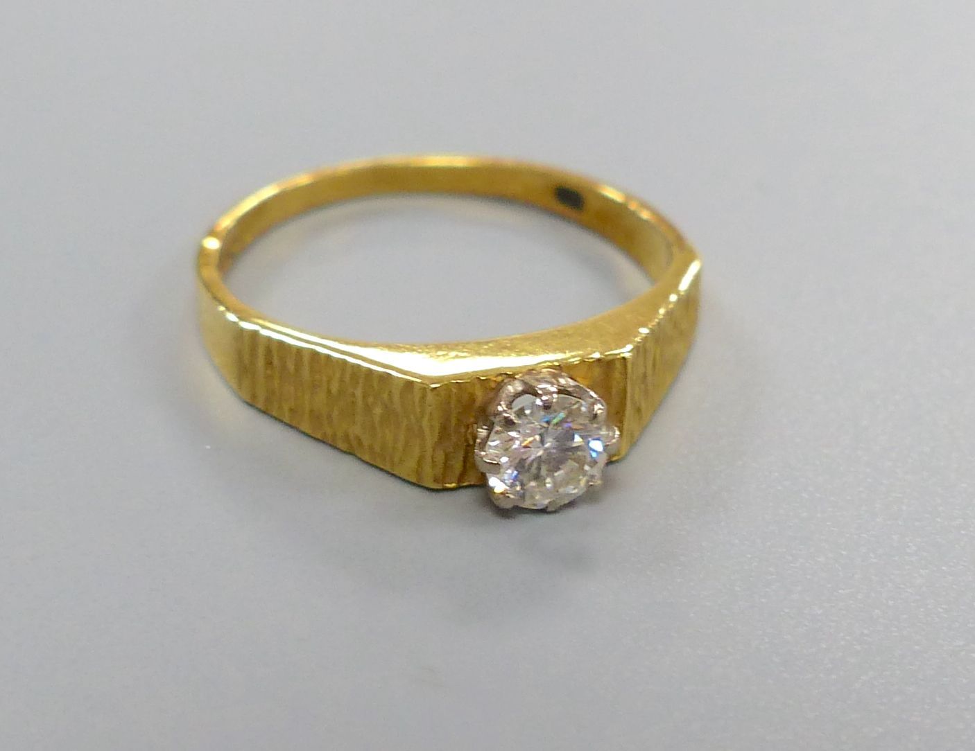 A modern 18ct gold and solitaire diamond ring, with textured shoulders, size N, gross 2.9 grams,